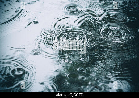 Schöne Hintergründe mit fallenden Wassertropfen in einer Pfütze im Regen Stockfoto