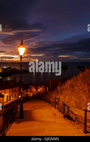 Whitby Stadt und der berühmten "199 Stufen" am Abend gegen einen dramatischen Sonnenuntergang. In Whitby, North Yorkshire, England. 12. a Stockfoto