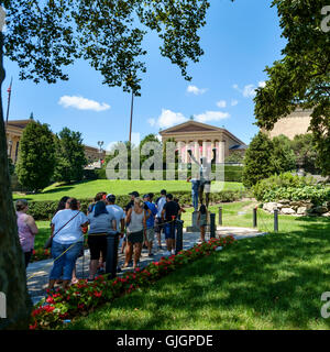 Menschen zu ihren Foto mit der Bronzestatue von Sylvester Stallone als Rocky Balboa außerhalb des Philadelphia Museum of Art Warteschlange. Stockfoto