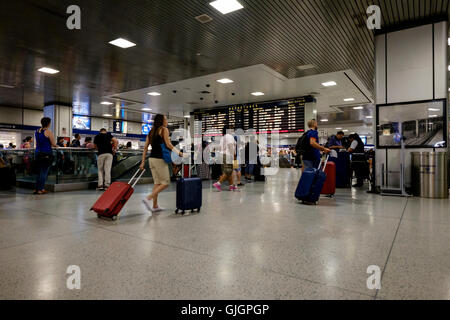 Fahrgäste überqueren das Foyer vor der Abfahrtstafel in Penn Station, New York Stockfoto