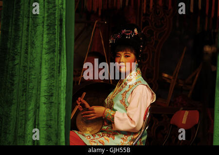 Eine Frau, gekleidet in klassischen Kostüm Spielmusik hinter dem Vorhang. Eine traditionelle Chu Chow ist bei GHOST FESTIVAL Oper um nicht nur für die lebenden, sondern auch für die Toten zu unterhalten, dass die Obdachlosen Geister, die die menschliche Welt durchstreifen unterhalten wird. Dieser symbolische Akt wird von Chinesen als ein Akt der Verdienst betrachtet. 16. August 2016. Hong Kong. 16. August 2016. Liau Chung Ren/ZUMA Liau Chung © Ren/ZUMA Draht/Alamy Live News Stockfoto