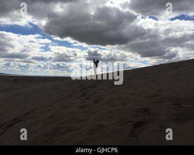 Silhouette eines Vaters, der Sohn im Rucksack trägt, Great Sand Dunes National Park, Colorado, USA Stockfoto