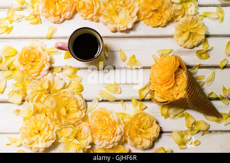 Gelbe Rosen, konzeptionelle Eistüte und Tasse Kaffee Stockfoto