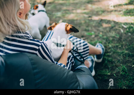 Frau sitzt auf dem Rasen mit zwei Hunden Stockfoto