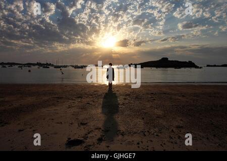 Silhouette einer Frau stehen am Strand bei Sonnenuntergang, Bretagne, Frankreich Stockfoto