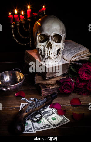 Stillleben mit einem Totenkopf an Rosen, Kerzenlicht, antiquarische Bücher, alte Pistole und Dollar-Noten Stockfoto