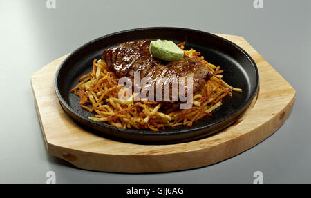 Rindersteak mit Kartoffeln in einer Pfanne und Kräuter butter Stockfoto