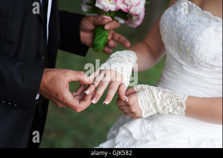 Bräutigam Braut umarmt, und in seinen Händen hält sie einen Brautstrauß Stockfoto