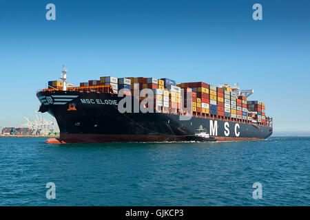 AMNAV Traktorschlepper Führung der riesigen Mediterranean Shipping Company Containerschiff, MSC Elodie zu Ihrem Liegeplatz im Hafen von Long Beach, Kalifornien, USA. Stockfoto