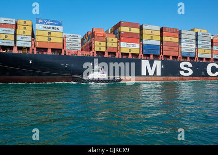 AMNAV Traktorschlepper Führung der riesigen Mediterranean Shipping Company Containerschiff, MSC Elodie zu Ihrem Liegeplatz im Hafen von Long Beach, Kalifornien, USA. Stockfoto