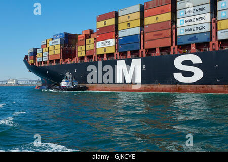 AMNAV Traktorschlepper Führung der riesigen Mediterranean Shipping Company Containerschiff, MSC Elodie, zu ihrem Liegeplatz im Hafen von Long Beach, Kalifornien, USA. Stockfoto