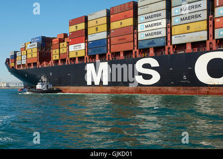 AMNAV Traktorschlepper Führung der riesigen Mediterranean Shipping Company Containerschiff, MSC Elodie zu Ihrem Liegeplatz im Hafen von Long Beach, Kalifornien, USA. Stockfoto