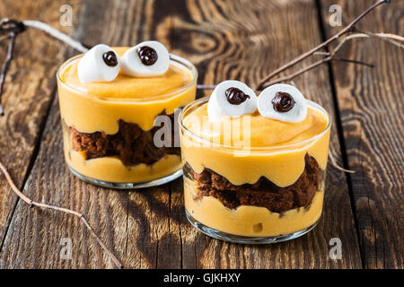 Halloween-Leckereien, kleines Monster-Dessert mit Schokoladen-Cookies und garniert mit großen Marshmallow Augen orange Mascarpone-Creme Stockfoto