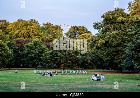 Touristen sitzen im St. James Park bei Einbruch der Dämmerung London UK Stockfoto