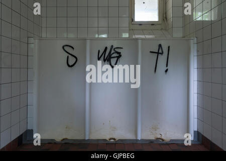 Eine schmutzige öffentliche Toilette mit drei Herren Urinale und schwarz graffiti Stockfoto