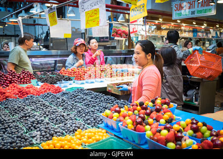 Ein Obsthändler hinter Berge von Obst auf Granville Island Public Market in Vancouver, British Columbia, Kanada. Stockfoto