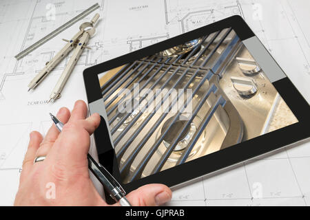 Hand des Architekten auf Computer Tablet zeigt Küche Herd Details über Hauspläne, Zirkel und Lineal. Stockfoto