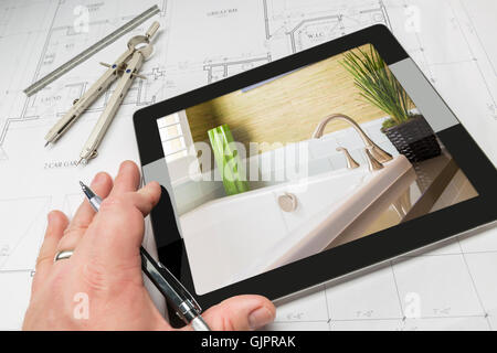 Hand des Architekten auf Computer Tablet zeigt Luxus Badezimmer Details über Hauspläne, Zirkel und Lineal. Stockfoto