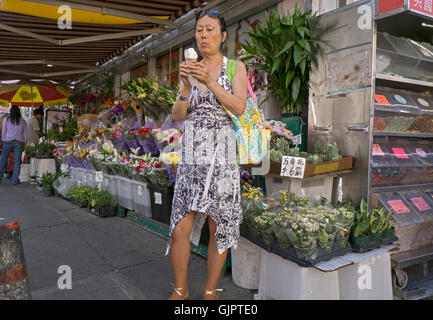 Ein asiatisch-amerikanische Frau, Essen ein Eis an einem heißen Sommertag auf Main St., Flushing, Queens, New York Stockfoto