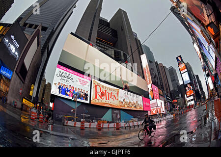 Ein einsamer Biker am Broadway, am Times Square Ion ein Wochenende früh kurz nach einem Regenschauer. Manhattan, New York City. Stockfoto