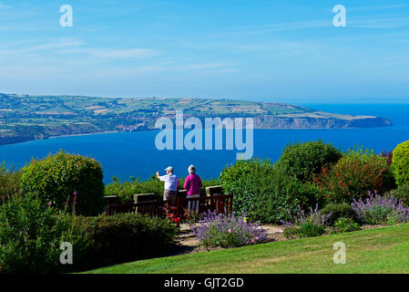 Älteres Paar im Garten von Raven Hall Hotel, Ravenscar, mit Blick auf Robin Hoods Bay, North Yorkshire, England UK Stockfoto