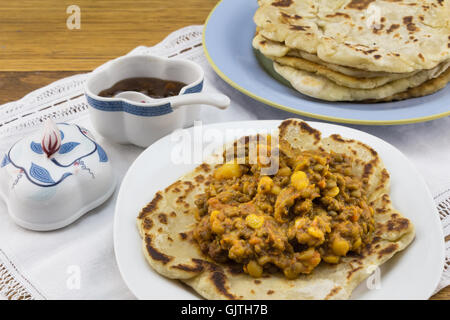 Indische Kichererbsen und Linsen curry mit Roti und Chutney auf weißer Spitze Stockfoto