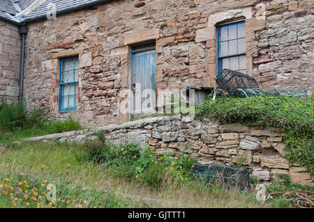 Ein sehr altes Landhaus aus Stein mit einem Schieferdach und verblichenen blauen Fenstern und Tür Stockfoto