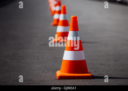 leuchtend orange Leitkegel stehen in einer Reihe auf dunklem asphalt Stockfoto