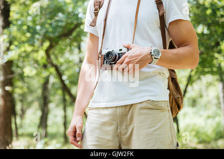 Nahaufnahme der junge Mann mit Rucksack und Vintage-Foto-Kamera im Wald Stockfoto