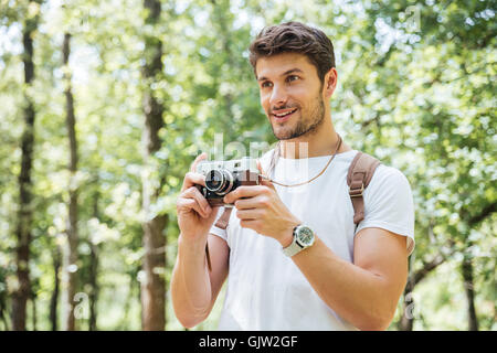 Glücklich Jüngling mit Rucksack fotografieren mit alten Foto-Kamera im Wald Stockfoto