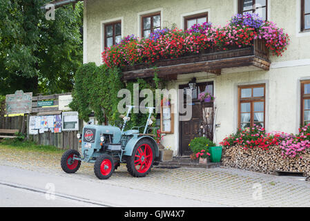 Eicher Diesel Oldtimer-Traktor vor dem Gasthaus Lindl geparkt bedeckt mit blühenden Geranien, Bayern, Deutschland Stockfoto