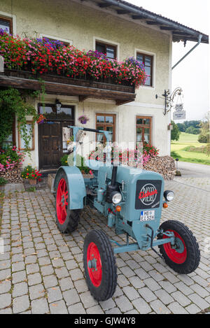 Eicher Diesel Oldtimer-Traktor vor dem Gasthaus Lindl geparkt bedeckt mit blühenden Geranien, Bayern, Deutschland Stockfoto