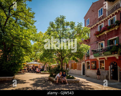 Paar, sitzen im Schatten des Baumes, auf einem Platz in Murano, Italien. Stockfoto