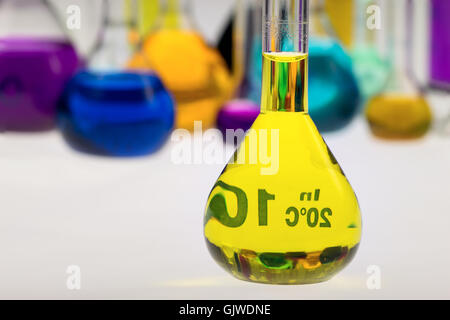 Kolben mit gelben Flüssigkeit vor anderen Fläschchen im chemischen Labor Stockfoto
