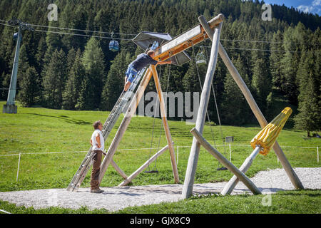 Arbeiter stieg auf eine Leiter, die Festsetzung einer Schaukel von einem Spielplatz in der Nähe der Seilbahn Stockfoto