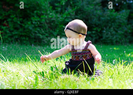 Babymädchen an etwa 6 Monate alt im Freien in einer natürlichen Umgebung mit vorhandenem Licht für ein Lifestyle-Porträt. Stockfoto