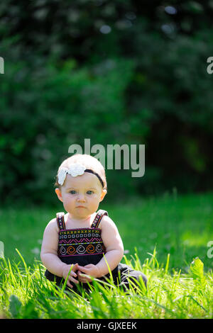 Babymädchen an etwa 6 Monate alt im Freien in einer natürlichen Umgebung mit vorhandenem Licht für ein Lifestyle-Porträt. Stockfoto