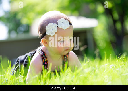 Babymädchen an etwa 6 Monate alt im Freien in einer natürlichen Umgebung mit vorhandenem Licht für ein Lifestyle-Porträt. Stockfoto