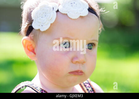 Babymädchen an etwa 6 Monate alt im Freien in einer natürlichen Umgebung mit vorhandenem Licht für ein Lifestyle-Porträt. Stockfoto