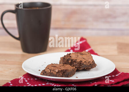 Hausgemachte Brownies mit Tasse im Hintergrund Stockfoto