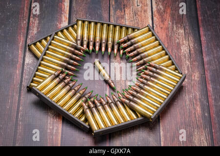 Munition,.223/556, in einem Muster die Form des Pentagons auf dunklen Holzoberfläche zu arrangieren. Stockfoto