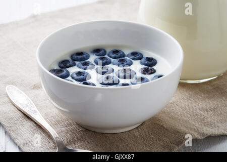 Schüssel mit frischen Heidelbeeren mit Milch serviert auf weißer Holztisch Stockfoto