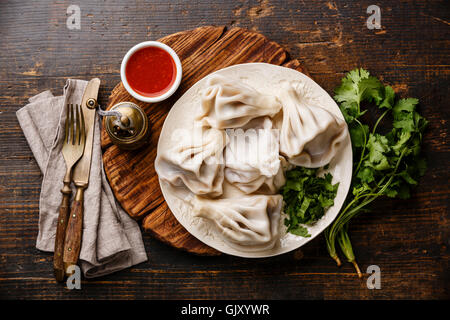 Georgische Teigtaschen Khinkali mit Fleisch und Tomaten pikante Sauce Satsebeli auf hölzernen Hintergrund Stockfoto