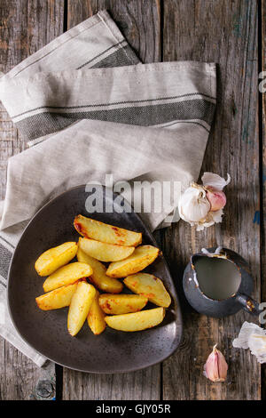 Land Bratkartoffeln auf braune Keramik-Platte, serviert mit hausgemachter Aioli Sauce in Krug, Knoblauch und Vintage Gabel auf Grau Leinen na Stockfoto