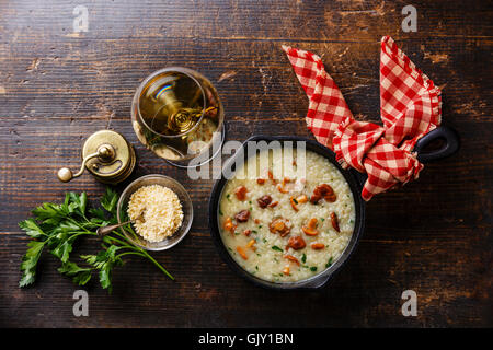 Risotto mit Pfifferlingen in Pfanne auf Holztisch Stockfoto