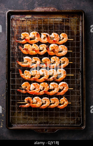 Gebratene Garnelen am Spieß auf Metallgitter Backen Blatthintergrund gegrillt Stockfoto