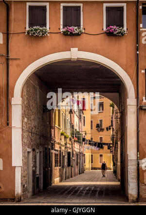 Älterer Mann mit einem Stock unter Linie Wäsche aufgehängt über den Weg laufen. Venedig, Italien Stockfoto
