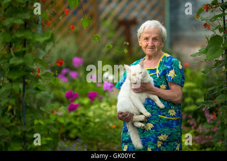 Ältere Frau mit einer Katze in der Hand lohnt im Garten sich. Stockfoto