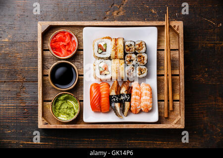 Sushi Set Nigiri und rollt mit Stäbchen, Ingwer, Sojasauce und Wasabi im Tray auf rustikalen hölzernen Hintergrund Stockfoto