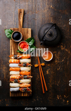 Nigiri Sushi set aus Holz dienen und grüner Tee auf dunklem Holz Stockfoto